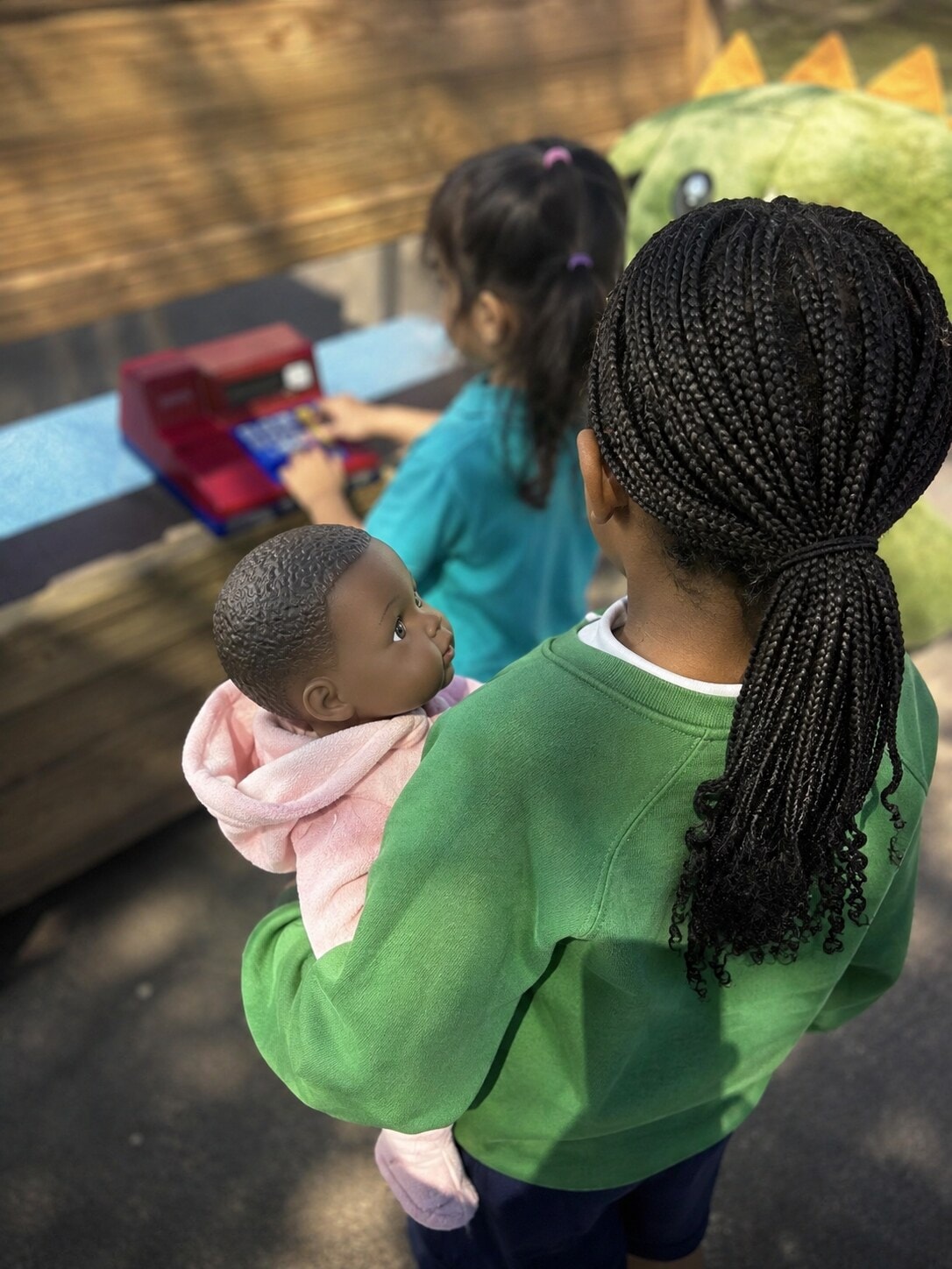 Children engaged in caring role play with a baby doll