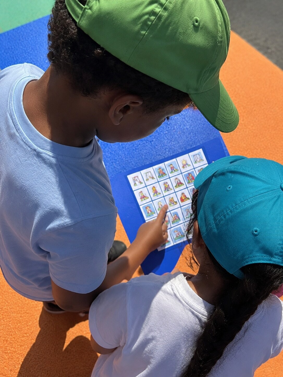 Two children looking at a cooperative playground game card together