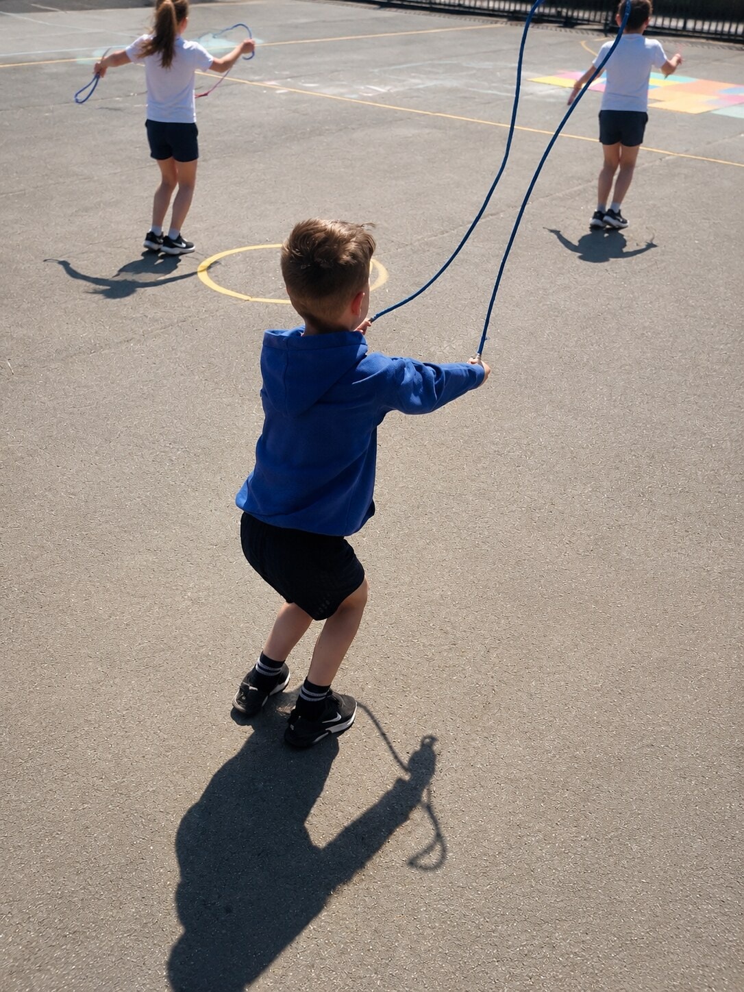 Children practising with blue skipping ropes on the playground